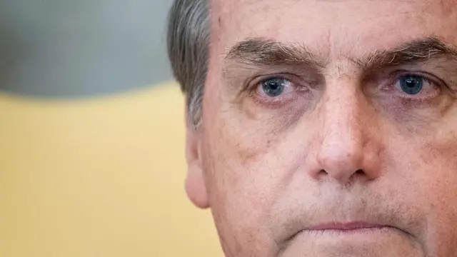 Foto com foco aproximado mostra Bolsonaro olhando para frente com olhar consternado