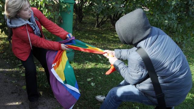 гей-активист и его противница рвут друг у друга из рук радужный флаг