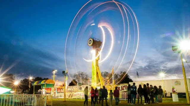 Jóvenes esperan su turno para subir a "la rueda de la fortuna", en un parque de juegos mecánicos que pasó por Osorno Chile.