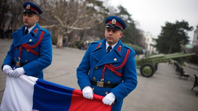 Soldados sérvios com a bandeira nacional durante celebração oficial da data do país