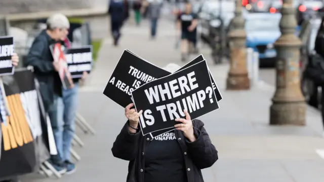 Mulher segura cartaz ‘Onde está Trump?’