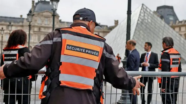 Empleados de seguridad instalan barreras cerca de la Pirámide de cristal del Museo del Louvre en París, Francia.
