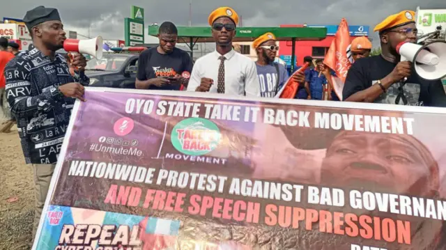 A man wit orange beret wit odas holding a banner