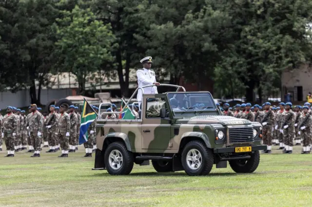 Un officier sud-africain dans un jeep passe en revue les hommes en treillis