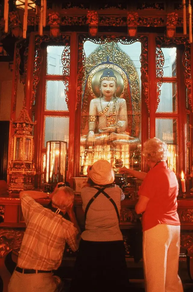 سياح غربيون في الصين يلتقطون صورا لتمثال لبوذا مصنوع من اليشم وهو من الأحجار الكريمة