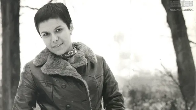 Elis sorrindo para foto, próxima de árvores