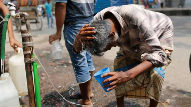 aşırı sıcakta suyla serinlemeye çalışan Hint bir adam . 