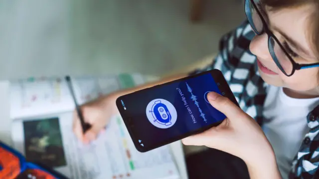 صبي يستخدم روبوت دردشة يعمل بالذكاء الاصطناعي على هاتفه بينما يقوم بإنجاز واجباته المدرسية