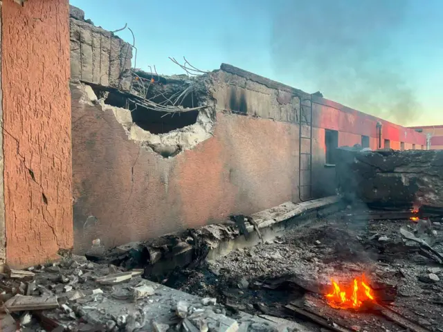 Зруйнована будівля та вогонь перед нею