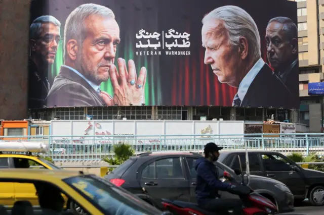 Um outdoor em Teerã mostrando o presidente iraniano e um líder da Guarda Revolucionária frente a frente com Biden e Netanyahu