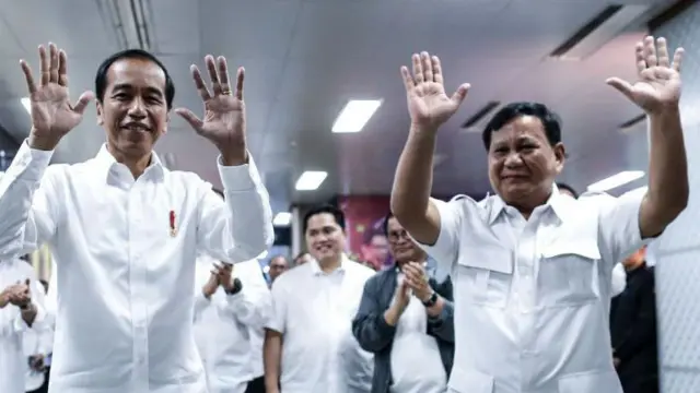 Joko Widodo (kiri) dan Prabowo Subianto (kanan) melambaikan tangan kepada wartawan selama pertemuan mereka di stasiun kereta bawah tanah di Jakarta, Indonesia, 13 Juli 2019.