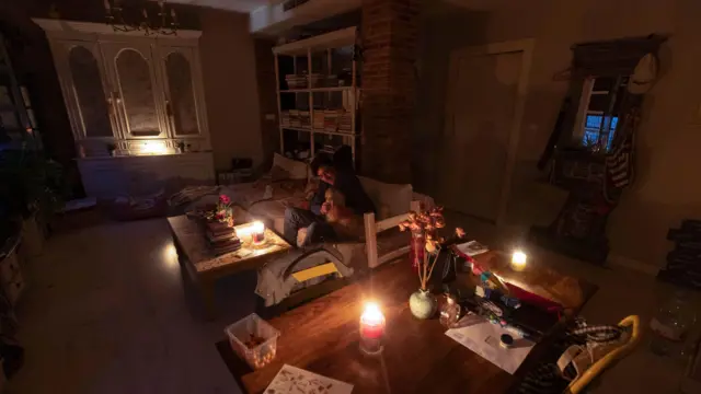 Murcia kentindeki evinde mumlarla oturan bir kişi.