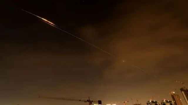 સોમવાર સવારે ઇઝરાયલના દરિયાકાંઠાના શહેરના આકાશમાં ઈરાની હુમલાની તસવીર, કેટલાક ખાડી દેશોનો દાવો છે કે તેમના ઍર ડિફેન્સ સિસ્ટમે મિસાઇલ અને ડ્રોન હુમલાને રોક્યા છે.