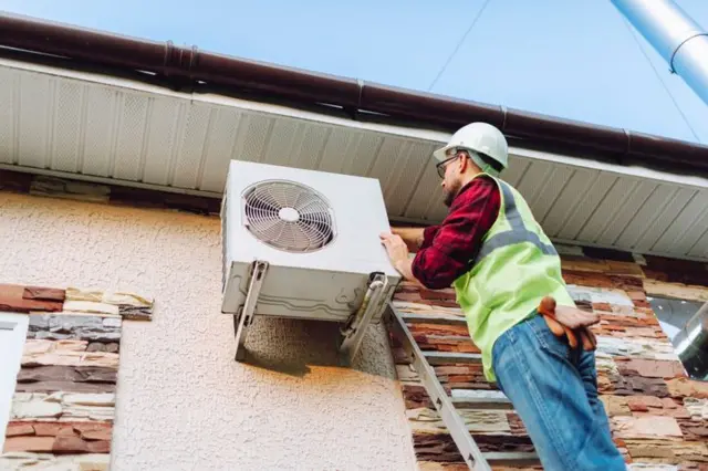 Homem instalando bomba de calor em casa