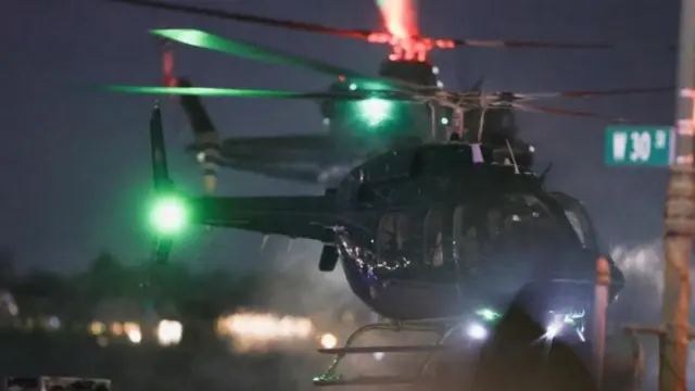 「西30番街」の道路標識が見える夜のヘリパッドに、複数の黒いヘリコプターが着地する様子。緑の尾灯が光っている