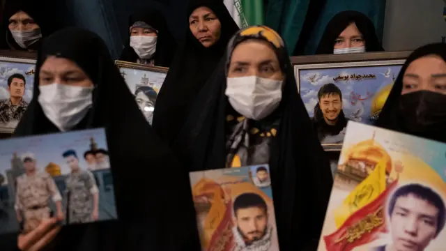 Afghan women hold portraits of their sons and relatives who were members of the Fatemiyoun Brigade and killed during the war in Syria.