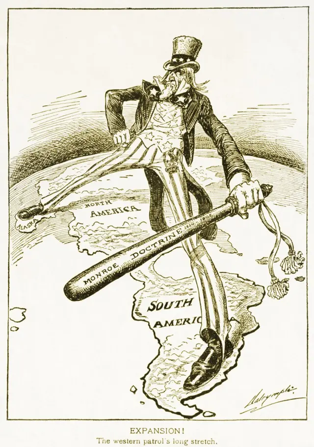 Caricatura política en la que el Tío Sam se extiende a ambos lados de América mientras blande un gran garrote con la inscripción 