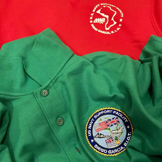 Uma camisa polo verde com o emblema "Instalação de Apoio da Marinha dos EUA - Diego Garcia, Biot"