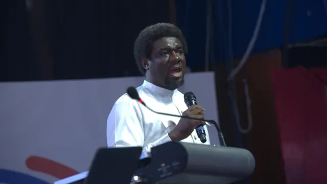 Pengassan President Festus Osifo wear white shirt with microphone for im hand as e dey speak for one event