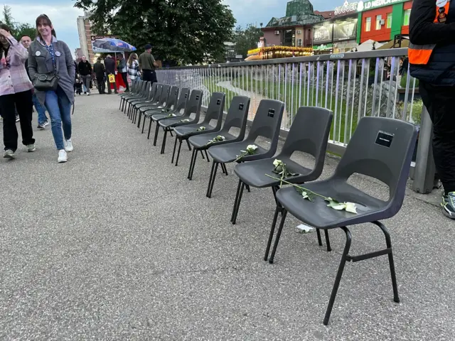 Crne stolice i bele ruže na njima na ulici