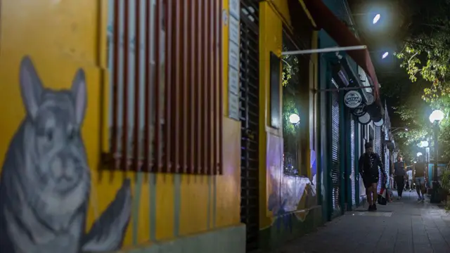 Pessoas caminhando numa calçada à noite