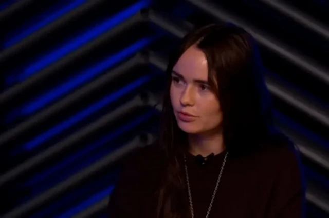 Молодая женщина с темными длинными волосами в темной одежде