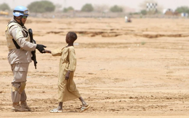 یک کودک با یک سرباز دست می‌دهد