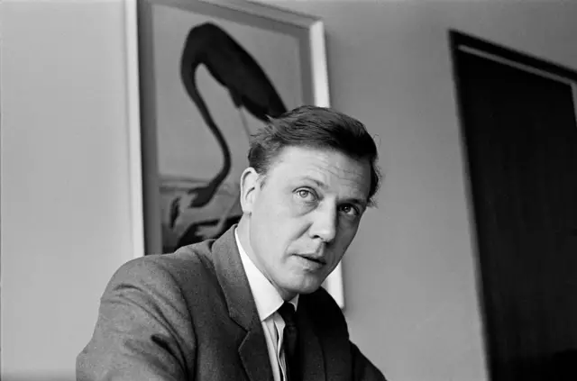 David Attenborough'nun BBC'de yönetilik yaptığı dönemde çekilmiş takım elbiseli siyah beyaz bir fotoğrafı. 