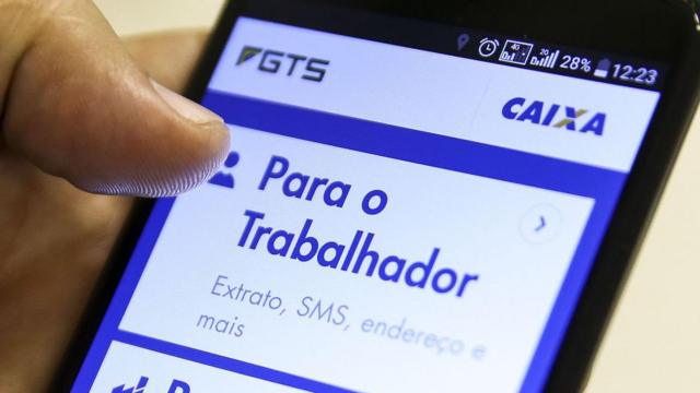 Mão segurando celular aberta na página do FGTS no aplicativo da Caixa