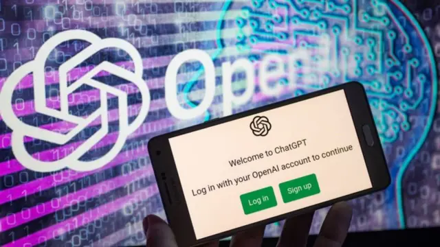 Celular com página do ChatGPTe logo da empresa OpenAI por trás