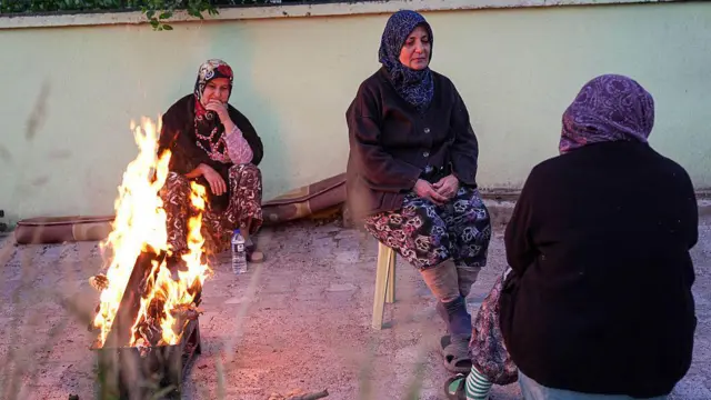 Sındırgı'da deprem sonrasında geceyi dışarıda geçiren kadınlar yanlarında ateş yakılmış bir halde oturuyor