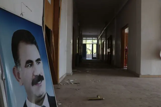 PKK lideri Abdullah Öcalan'ın posteri bir duvara yaslanmış, arkasında boş bir koridor var