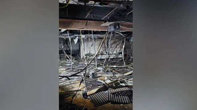 Paneles metálicos que cuelgan del techo de una habitación. Paneles y otros postes metálicos cubren el suelo.