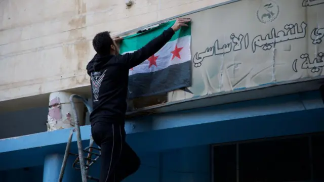Сирия: мужчина вешает флаг 