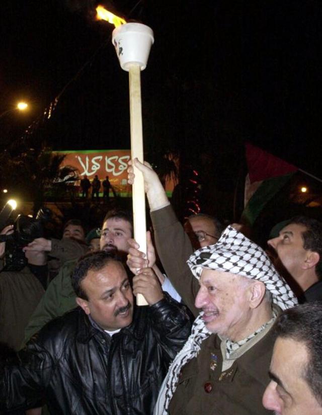 Yasser Arafat (R) and the head of his Fatah movement in the West Bank Marwan Barghuti (L) hold up a torch together in Ramallah on 31 December 2001 during a rally organised by Fatah, the main faction of the Palestine Liberation Organisation (PLO)