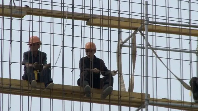 공사 중인 구조물에 올라가 있는 두 명의 남성 작업자
