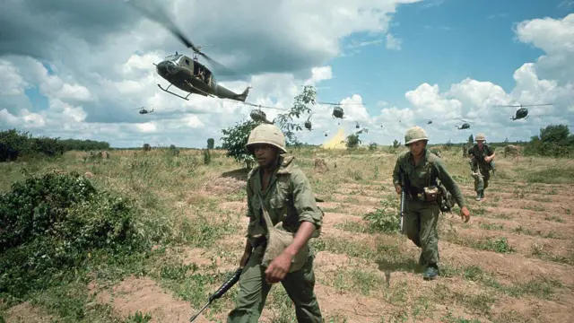 Soldados norte-americanos caminhando por um campo no Vietnã