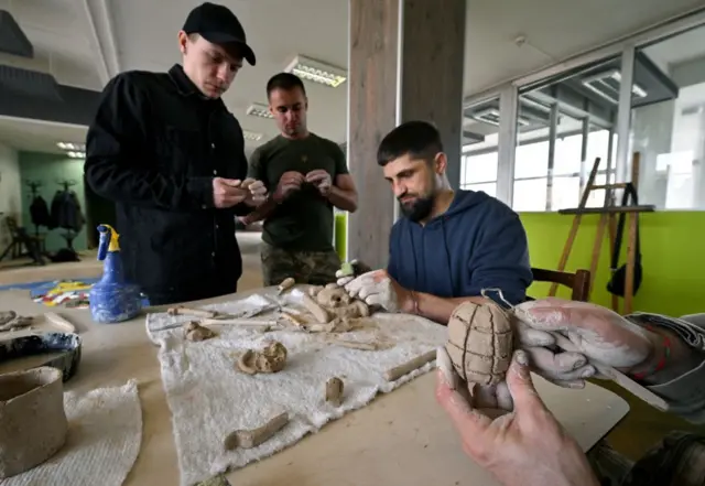 एक वर्कशाप में मिट्टी के खिलौने बनाते युद्ध में घायल हुए यूक्रेन के सैनिक