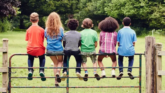 Um grupo muito diversificado de crianças sentadas em cima do muro