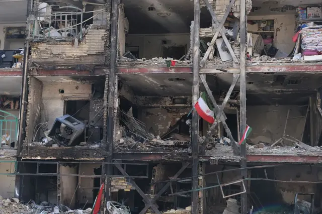 Иранские флаги висят на здании в жилом комплексе Шахид Боруджерди на юго-востоке Тегерана, которое было сильно повреждено и разрушено Израилем и США в ходе операции «Эпическая ярость» днем ​​ранее. Фотография сделана 5 марта 2026 года в Тегеране, Иран