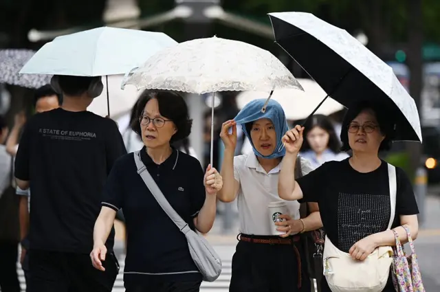 4일 서울에서 시민들이 양산으로 뜨거운 햇볕을 피하고 있다