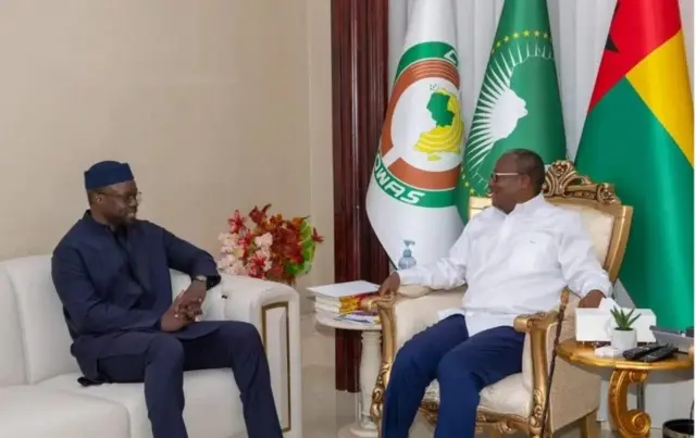 Ousmane Sonko, Premier ministre sénégalais (à gauche), vêtu d'un ensemble bleu foncé avec un chapeau sur la tête, et Umaru Sissoco Embalo le président bissau-guinéen en chemise blanche et pantalon bleu.