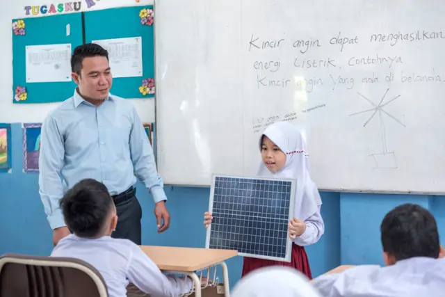 Seorang murid perempuan presentasi di depan kelas.