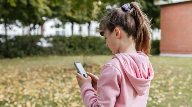 Una niña mirando un teléfono móvil