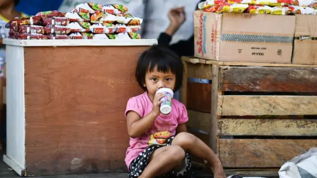 Seorang anak mengkonsumsi minuman kemasan gelas jus di pasar tradisional Palu, Sulawesi Tengah.
