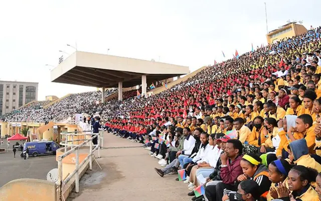 ዝተፈላለየ ሕብሪ ዘለዎ ልብሲ ቤት-ትምህርቲ ዝተኸደኑ ተመሃሮ ኣብቲ ኣብ ማእከል ንእሽቶ ጽላል ዘለዎ ደረጃታት ሜዳ ባሕቲ መስከረም ብዕቱብ ገጻት እናተኸታተሉ።