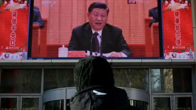 Fotoo que é freebet ktouma pessoao que é freebet ktocostas e na frente dela, uma TV com o líder chinês Xi Jinping falandoo que é freebet ktoum microfone. 