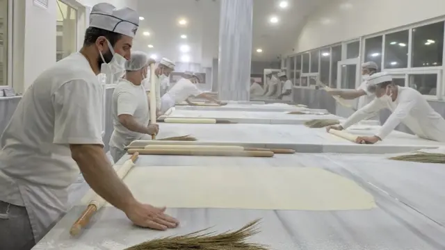 Piekarze w piekarni İmam Çağdaș rozwałkowują ciasto na cienkie płaty, przez które można zrobić baklawę