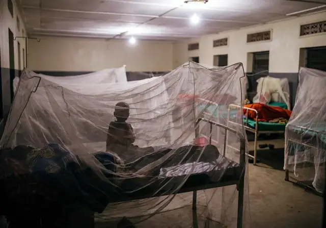 Un enfant patient dans un hôpital de campagne ou une clinique, protégé par une moustiquaire. 
