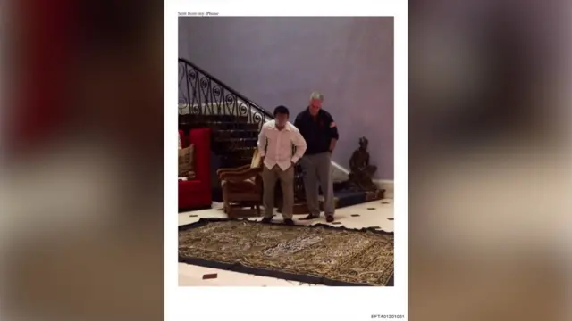 ABD Adalet Bakanlığı arşivlerinden bir fotoğrafta, Jeffrey Epstein ve yanındaki başka bir adamın, yerde duran işlemeli bir kumaş parçasına baktıkları görülüyor.